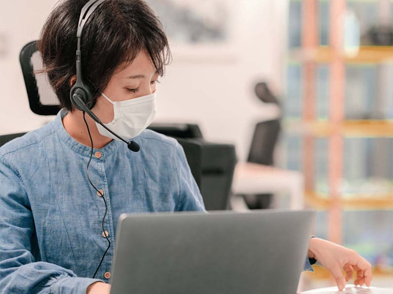 Honor professional wears face mask while working on laptop