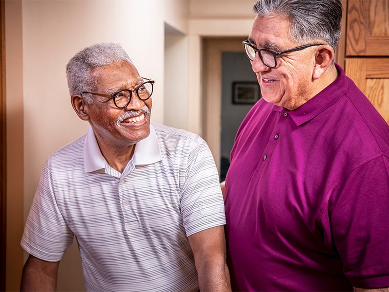 Aging man smiling while receiving help from a care professional